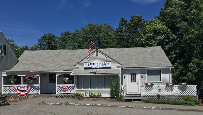 The salon's white clapboard shopfront with hanging sign, flower boxes and porch bunting